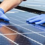 Male worker hands in glows on solar panel, technician installing solar panels on roof. Alternative energy sun energy power, ecological concept. Long web banner.